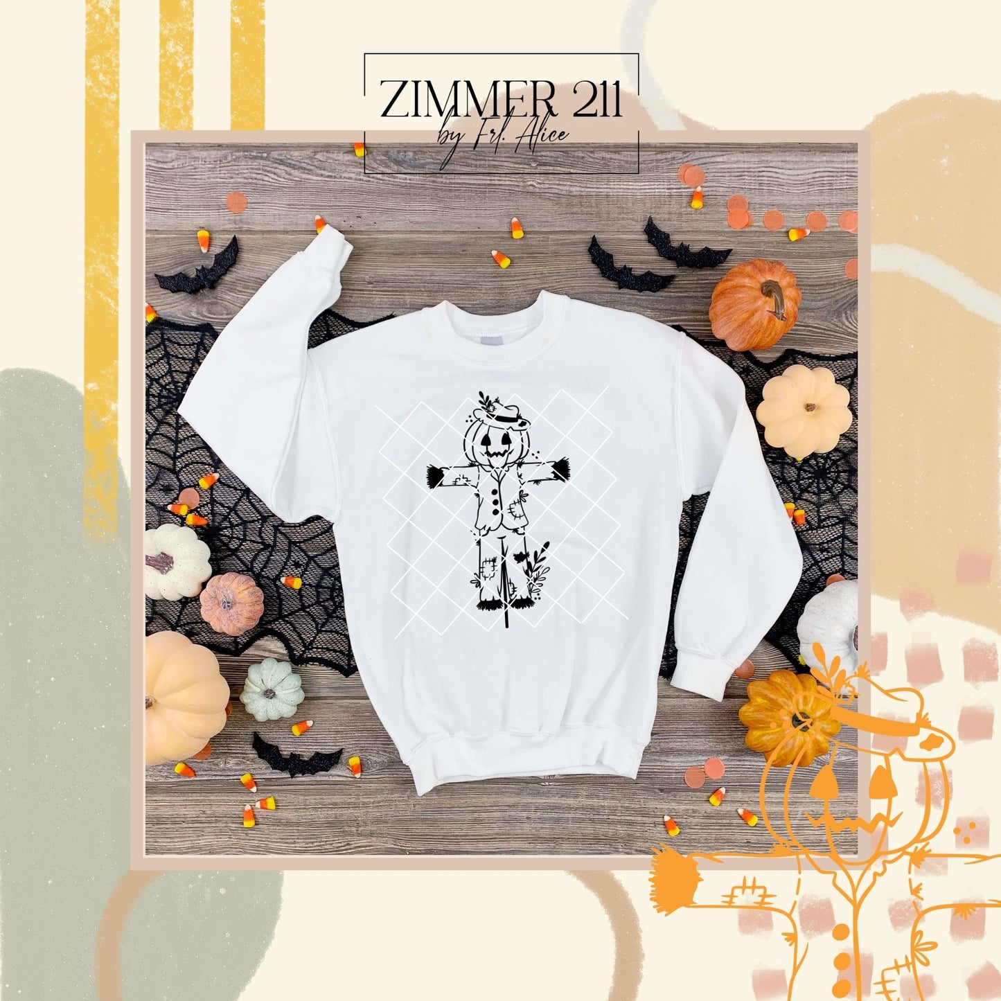 Weißes Sweatshirt flach liegend (Flatlay) mit schwarzem Vogelscheuchen-Design, dekoriert mit kleinen Kürbissen, Süßigkeiten und Fledermäusen.