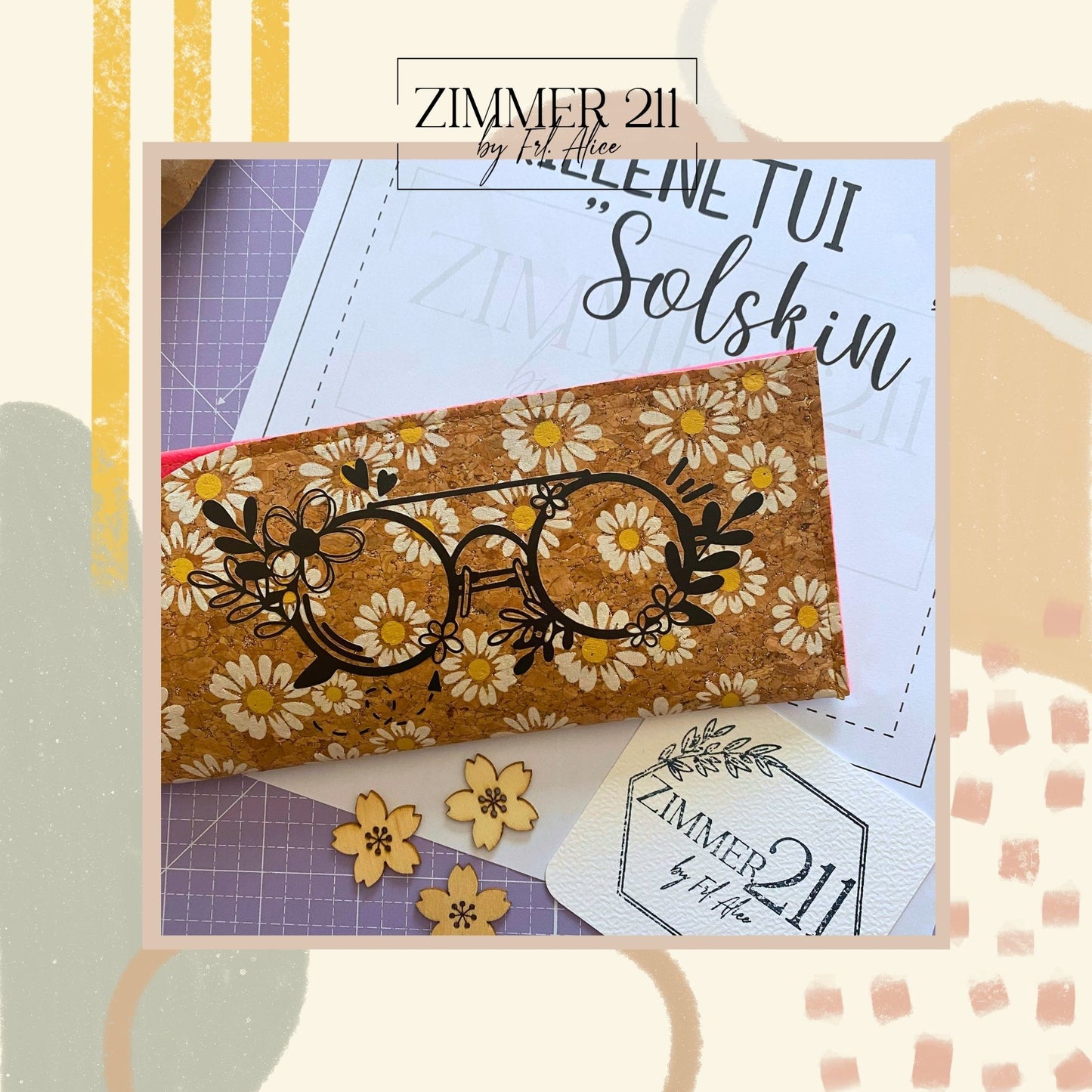 Produktfoto eines selbstgenähten Brillenetuis auf einer lila Schneidematte von „Zimmer 211 by Frl. Alice“. Das Etui besteht aus einem Korkstoff, der mit einem Gänseblümchen-Muster bedruckt ist, und hat ein neonpinkes Innenfutter. Auf der Vorderseite befindet sich ein schwarzer Plott einer Brille mit Blumenverzierungen. Das Etui liegt auf der ausgedruckten PDF-Nähanleitung mit dem Titel „Brillenetui Solskin“. Im Vordergrund sind drei kleine Deko-Holzblüten und ein Kärtchen mit dem Logo der Designerin platzie